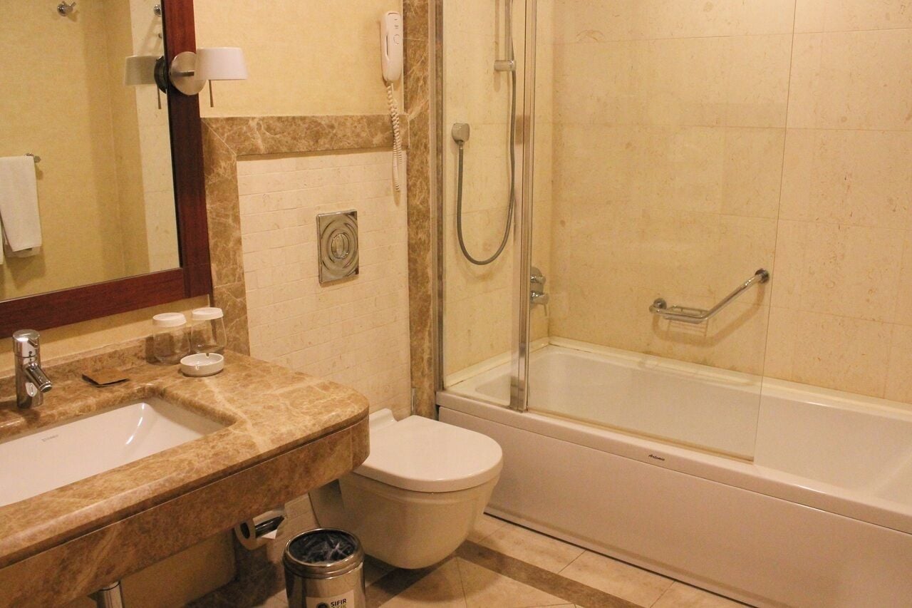 Un baño con lavamanos, inodoro y ducha con mampara de vidrio.