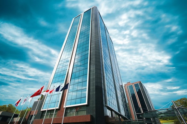 A tall, modern building with a glass facade and multiple flags. - Byotell Istanbul (Istanbul)