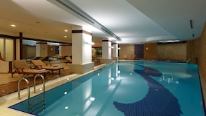 A large indoor swimming pool with a tiled design, lounge chairs, and a pool ladder. - Byotell Istanbul (Istanbul)