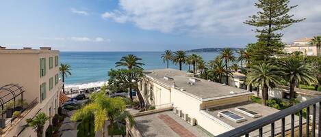 A coastal view with buildings, palm trees, and a clear sky.
