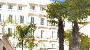 A courtyard with palm trees, a glass building, and a pathway.