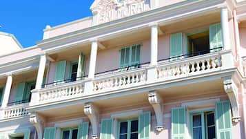 Un bâtiment rose doté de balcons et de volets verts.