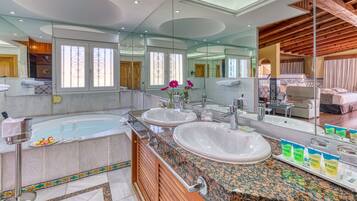 A luxurious bathroom with a large bathtub, two sinks, and a vanity area.