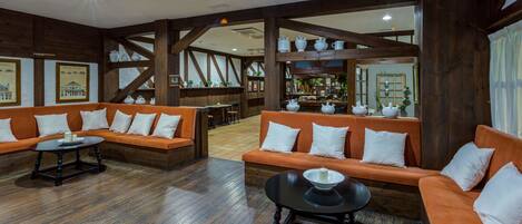 Eine geräumige Lobby mit Holzbalken, orangefarbenen Sofas und einem zentralen Tisch.