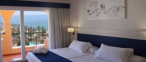 Une chambre d’hôtel avec un grand lit, une vue sur l’océan et un balcon avec une piscine.