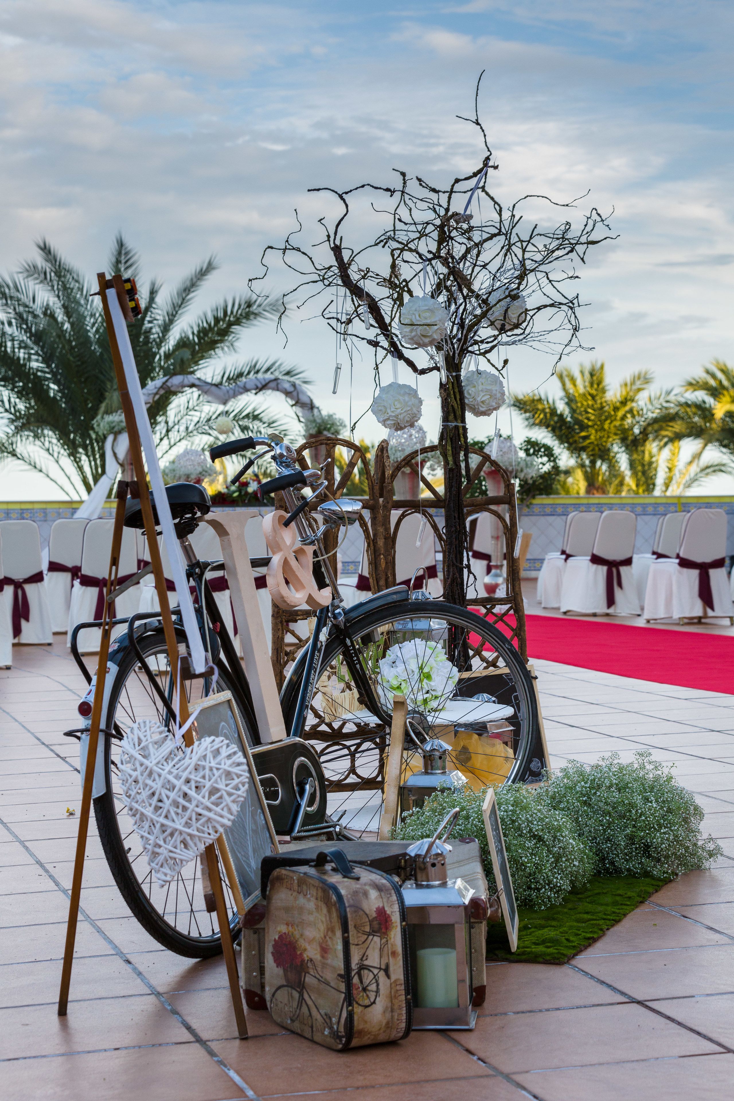 A bicycle with a basket, a vintage suitcase, and a bicycle wheel mounted on a stand.