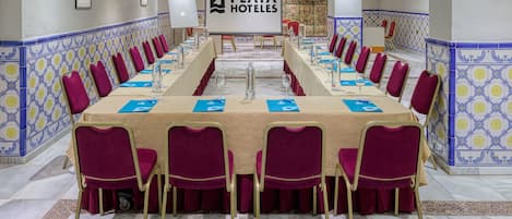 Un salón de conferencias con una larga mesa, sillas rojas y una pantalla proyectora mostrando el logotipo de Playa Hotels.