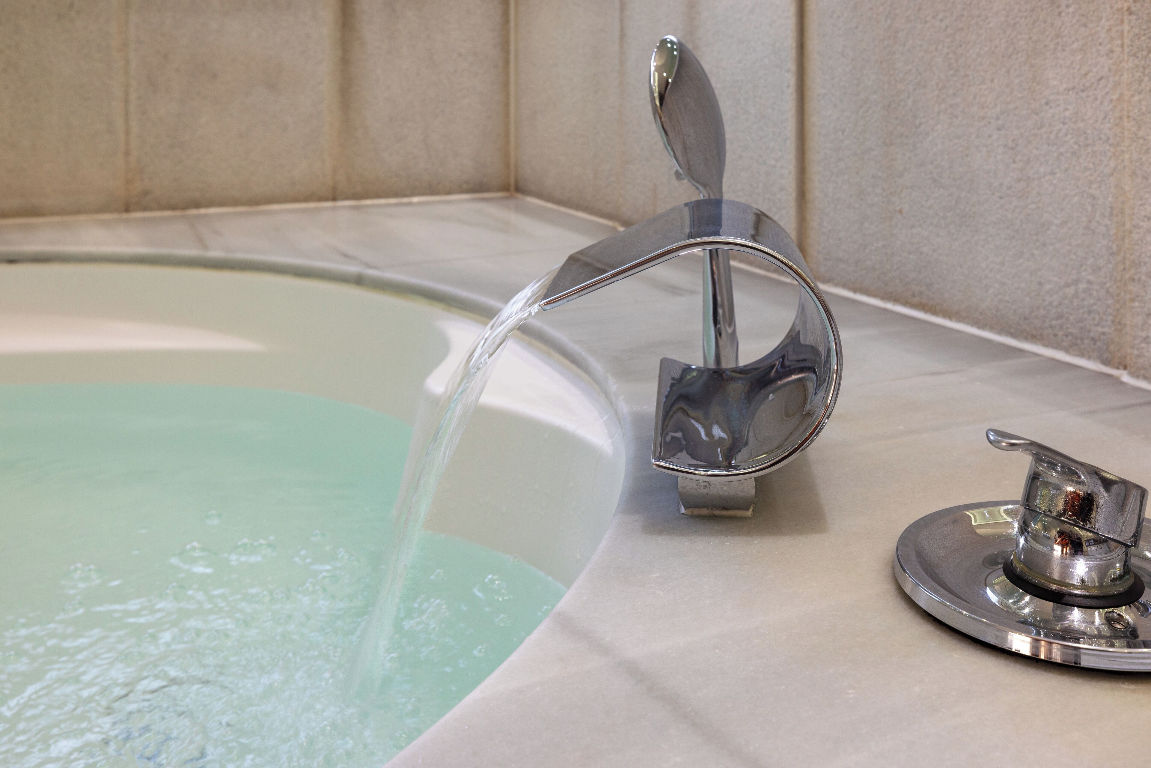 A bathtub with a chrome faucet and a separate control knob.