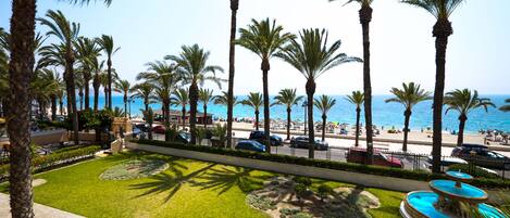 A landscaped area with palm trees, a fountain, and a view of the beach and ocean.