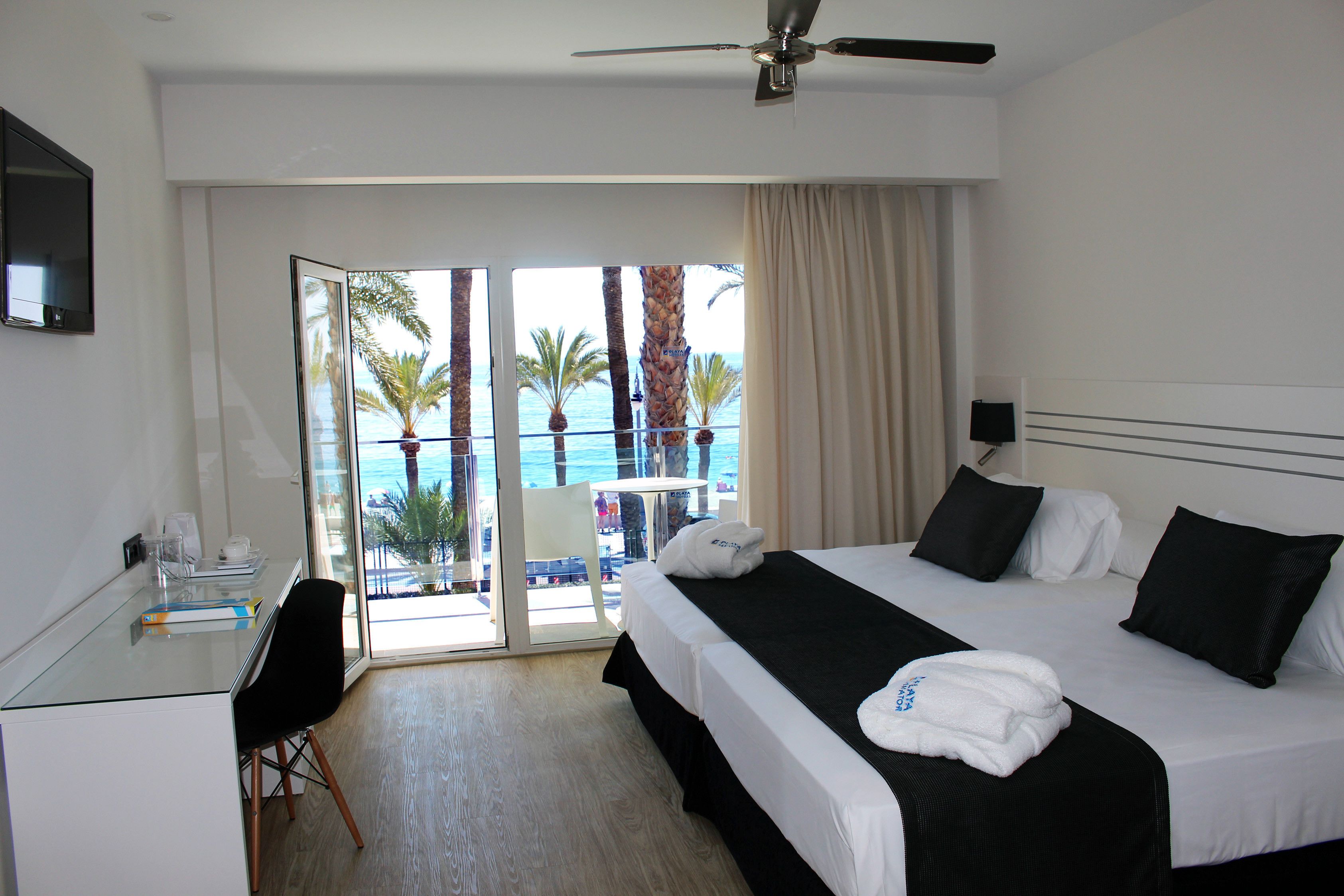 Habitación de hotel con cama, escritorio y vista al océano.