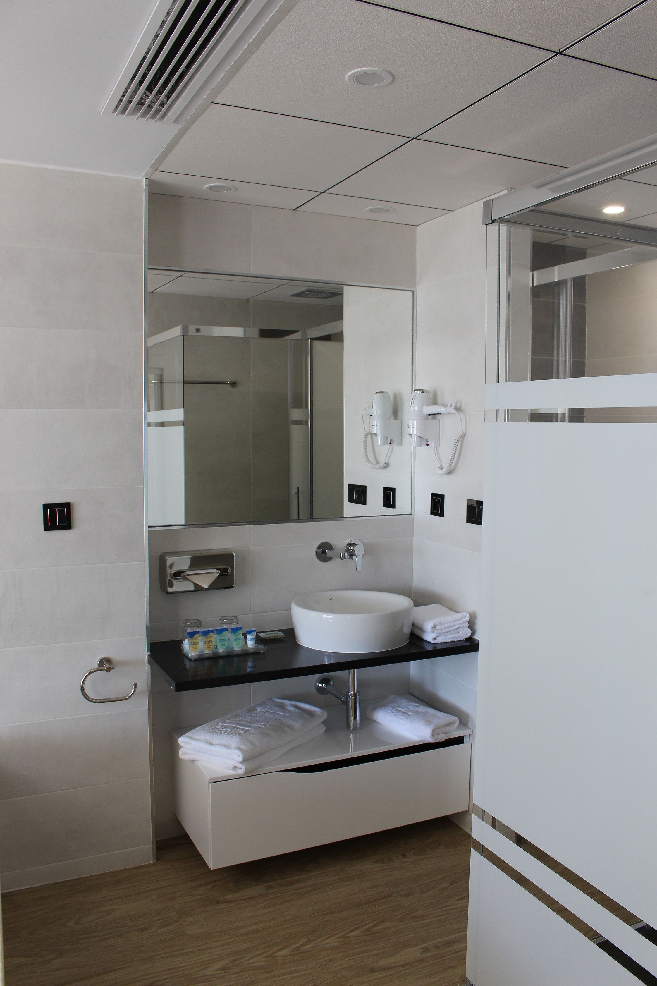 Un baño moderno con lavamanos, espejo y toallero blancos.