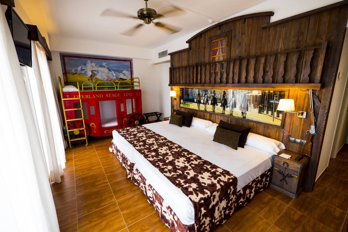 Ein Schlafzimmer mit einem großen Bett, einem Holzkopfstück, einem roten Etagenbett und einem Wandgemälde.