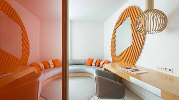 Una habitación moderna con un sofá curvo, un escritorio de madera y un espejo grande con marco de madera.