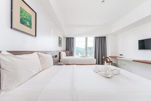A hotel room with a large bed, a TV, a window with curtains, and a framed picture on the wall. - Crown Regency Hotel and Towers (Cebu City)