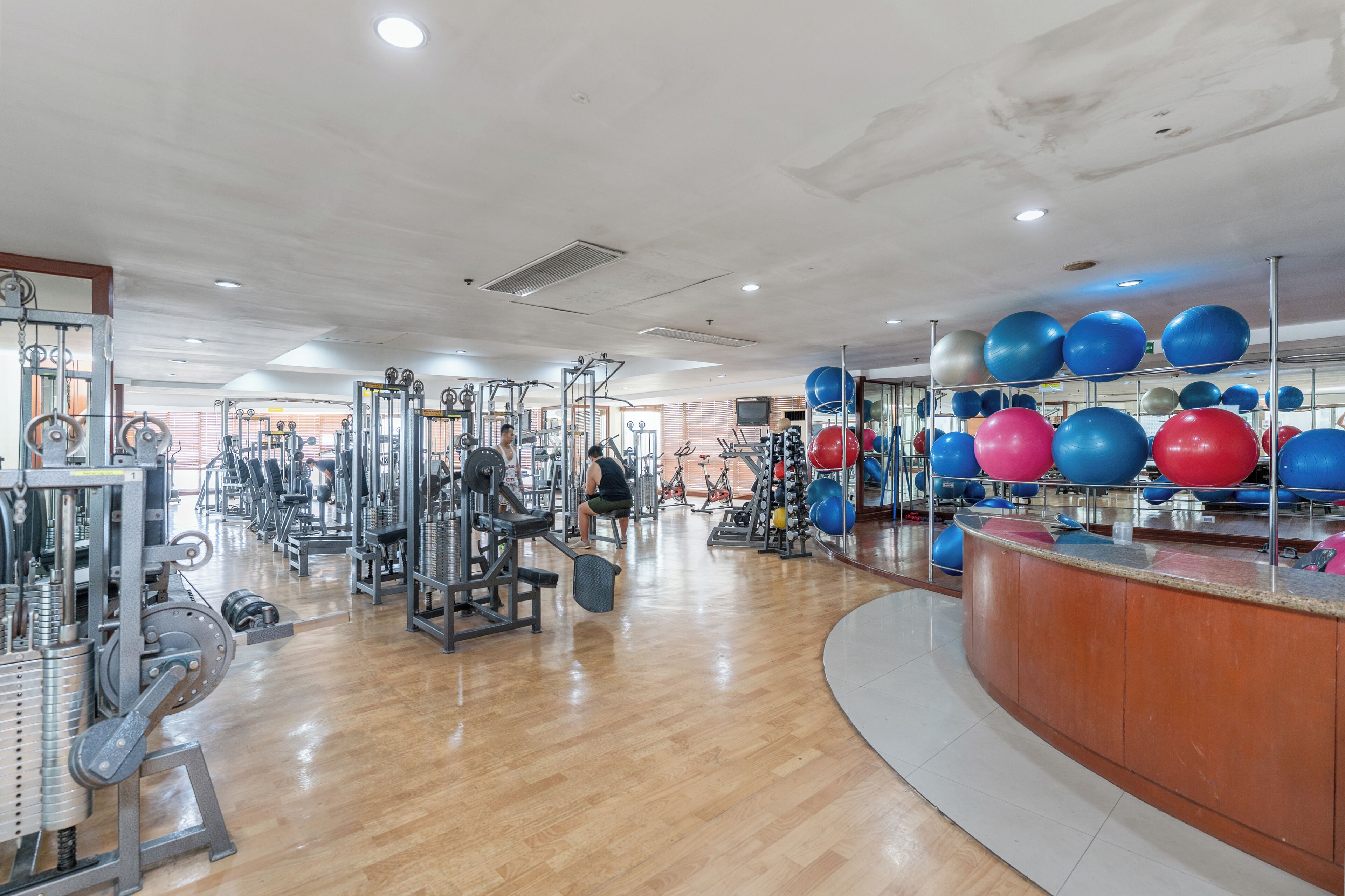 A gym with exercise equipment, a reception desk, and a variety of fitness balls.