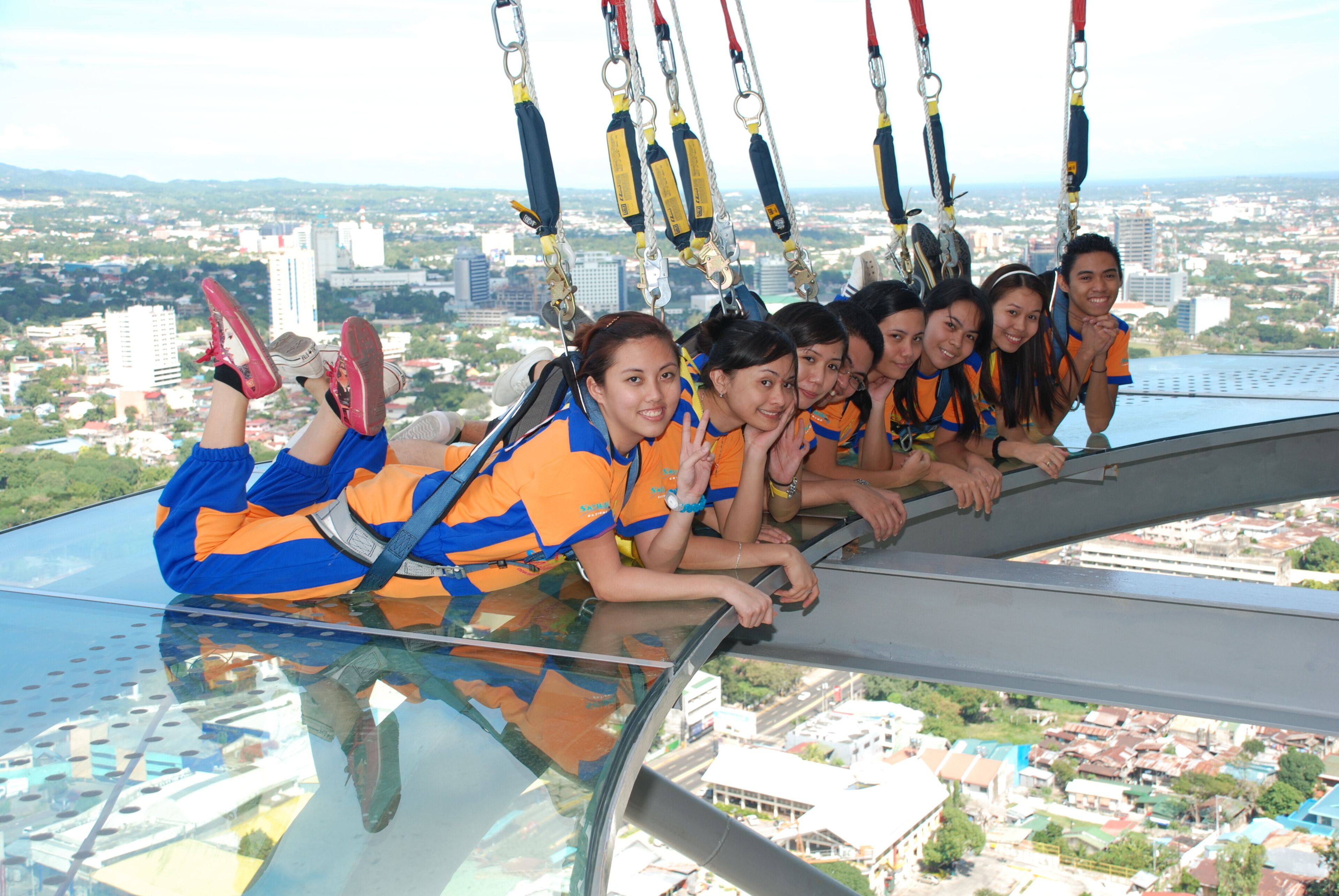 A group of people on a glass floor with a city view.