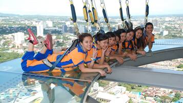 A group of people on a glass floor with a city view.