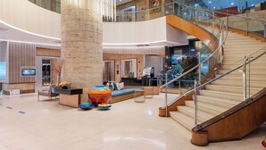 A spacious lobby with a central column, a staircase, and a seating area. - Crown Regency Hotel and Towers (Cebu City)