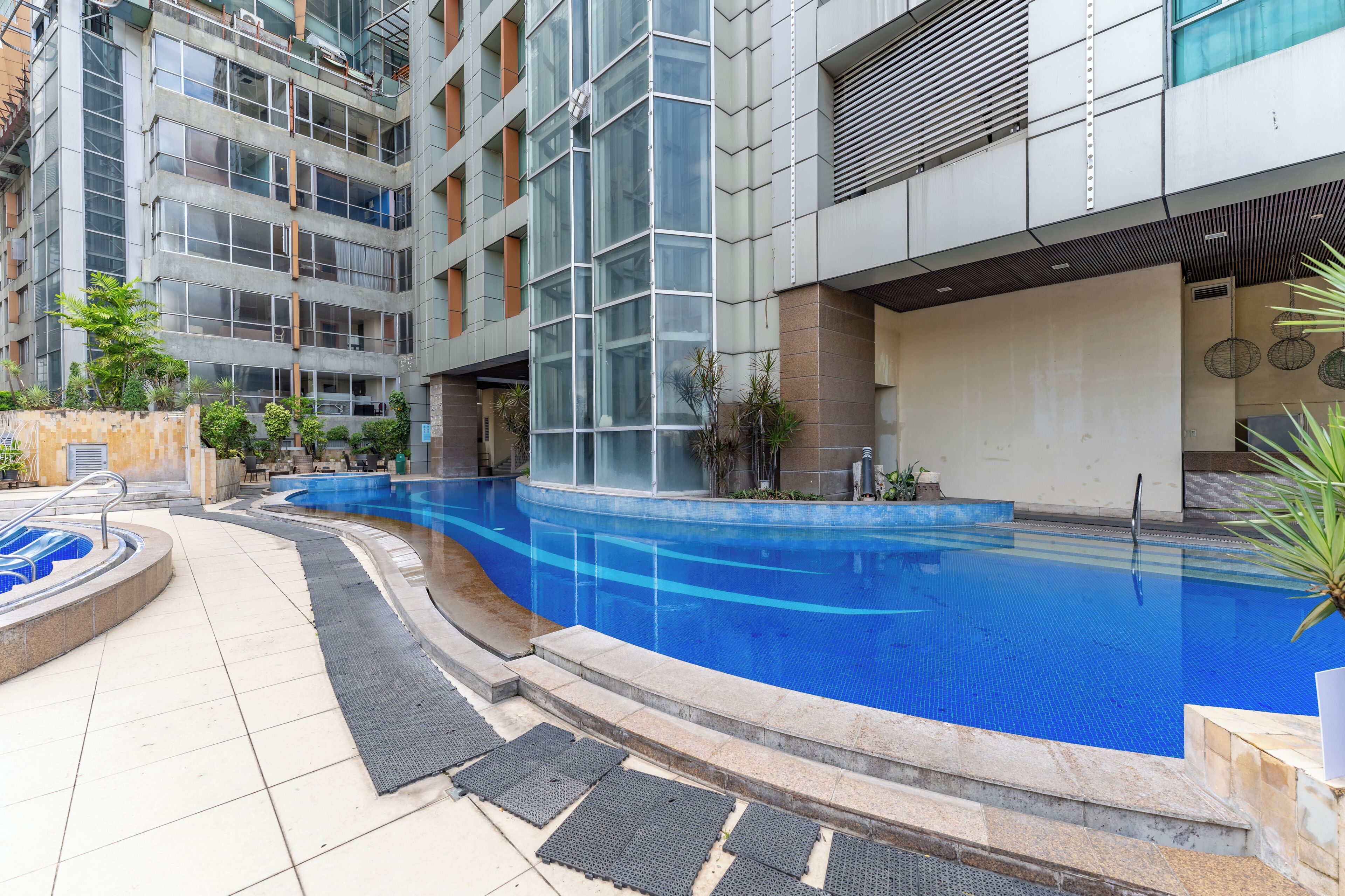 A modern building with a swimming pool, outdoor seating, and a covered area.