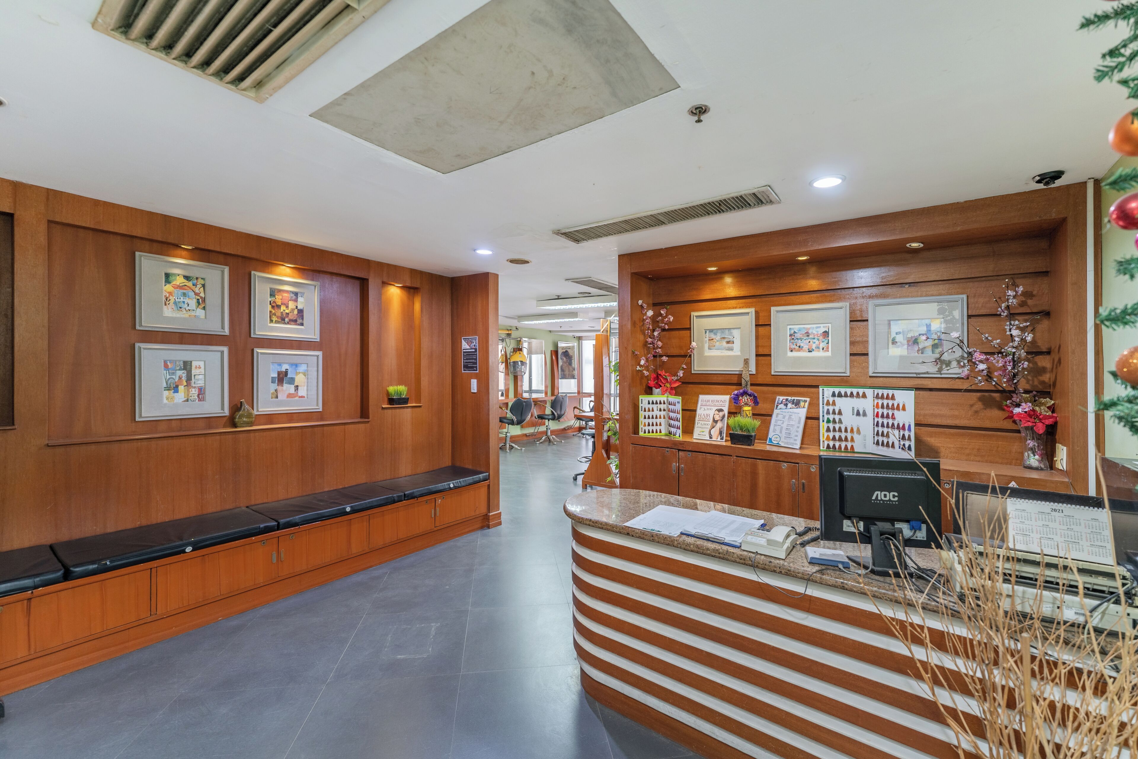 A reception area with a wooden bench, framed pictures on the wall, a reception desk, and a calendar.