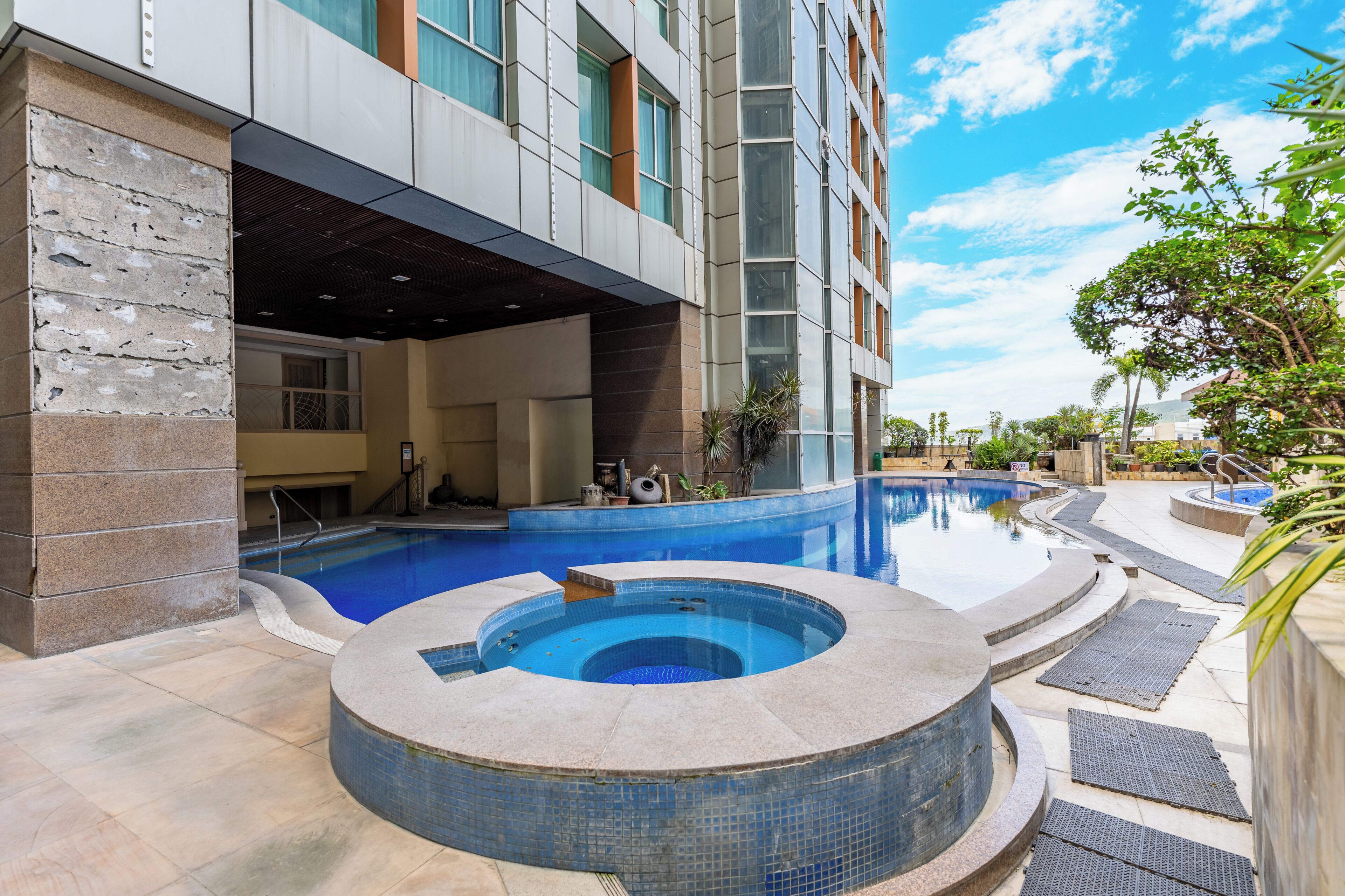 A modern building with a swimming pool, a hot tub, and a covered outdoor area.