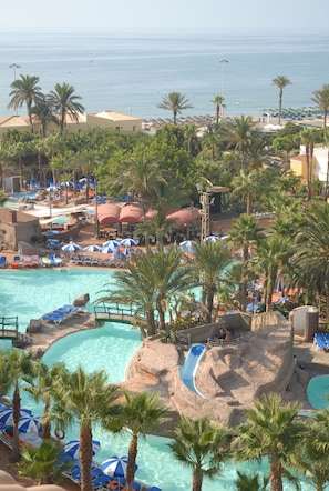 A resort with a large pool, palm trees, and a view of the sea. - Playasol Hotel (Roquetas de Mar)