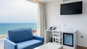 A modern room with a blue sofa, a glass coffee table, a small white desk, and a TV mounted on the wall. - Playasol Hotel (Roquetas de Mar)