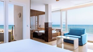 A modern hotel room with a large bed, a sofa, a bathroom with a large mirror, and a view of the sea. - Playasol Hotel (Roquetas de Mar)