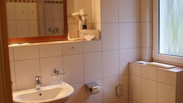 A bathroom with a sink, toilet, and a window.