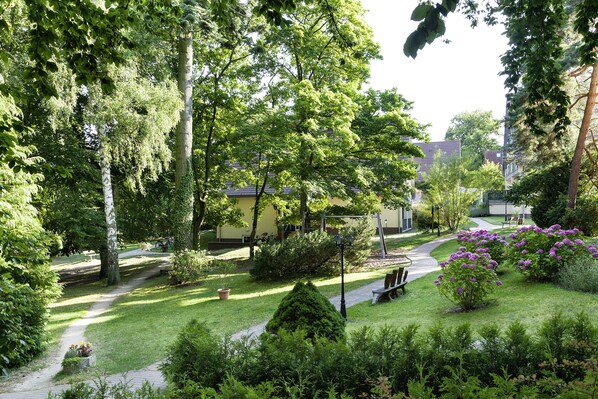 Un jardín bien cuidado con un sendero, bancos y plantas en flor.