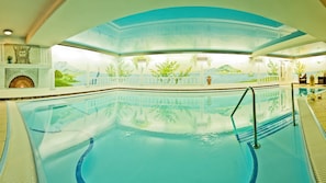 Una piscina cubierta, una piscina al aire libre, sombrillas, tumbonas