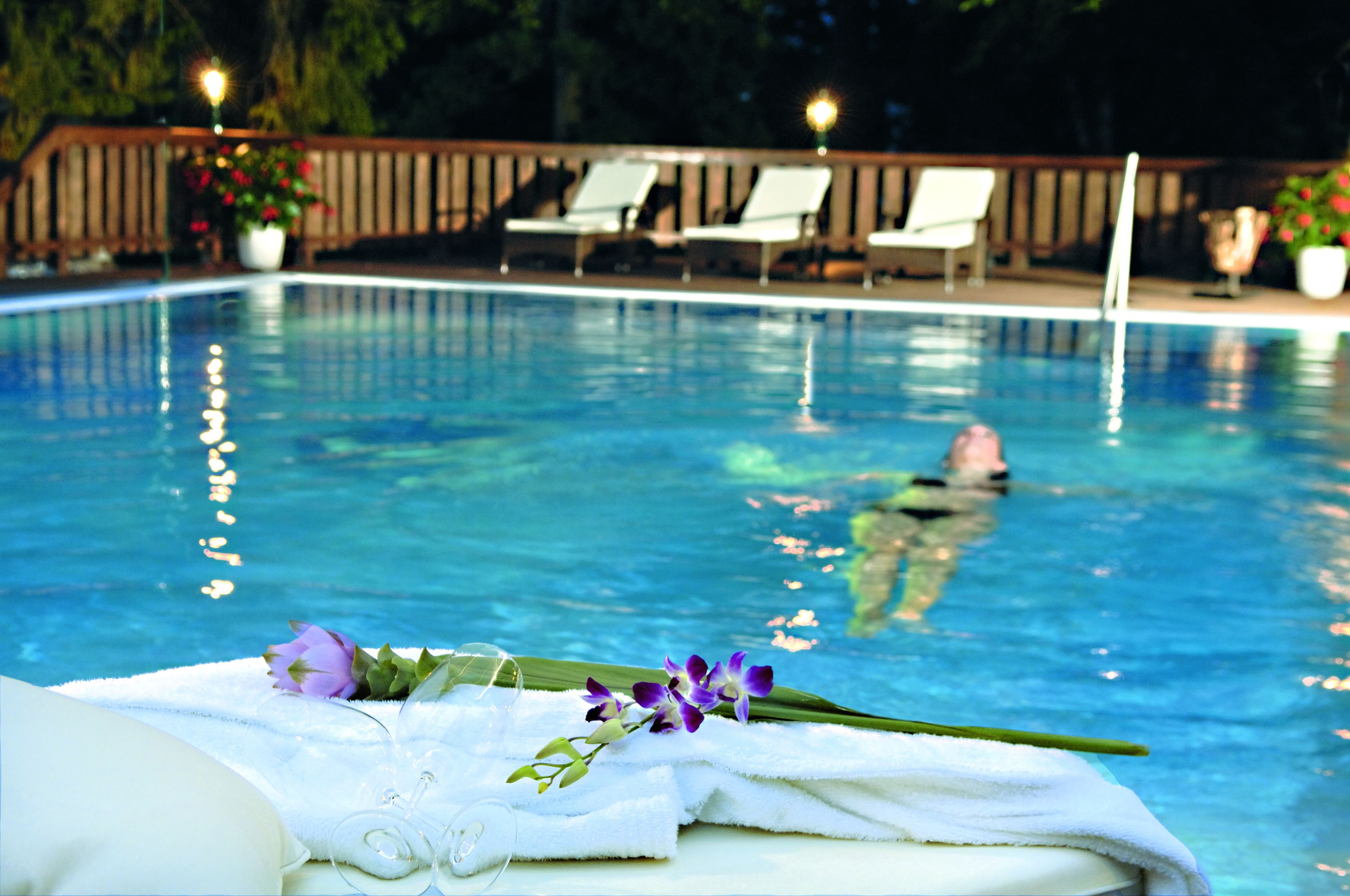 A swimming pool with lounge chairs and a person swimming.