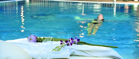 A swimming pool with lounge chairs and a person swimming.