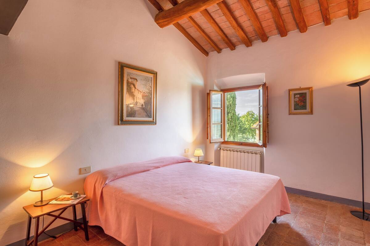 A bedroom with a bed, a window, a radiator, and a lamp.