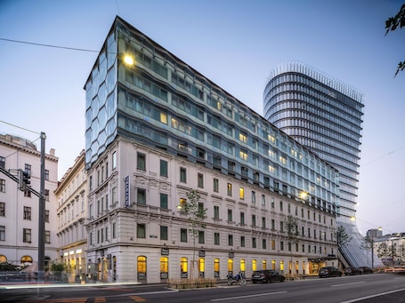 A modern hotel with a classic facade, large windows, and a distinctive curved glass tower.. Novotel Wien City