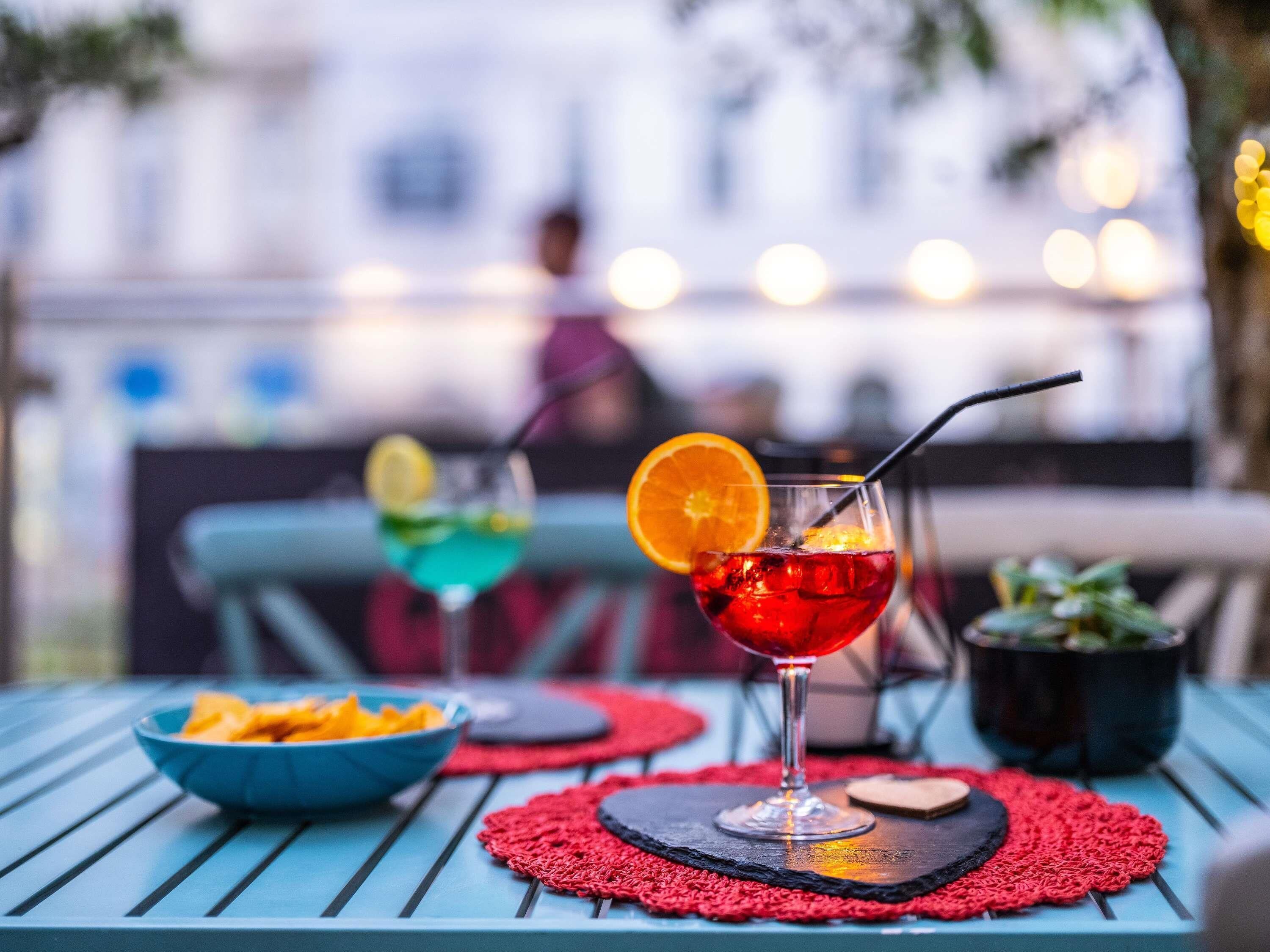 A table with two drinks, a bowl of snacks, and a potted plant.