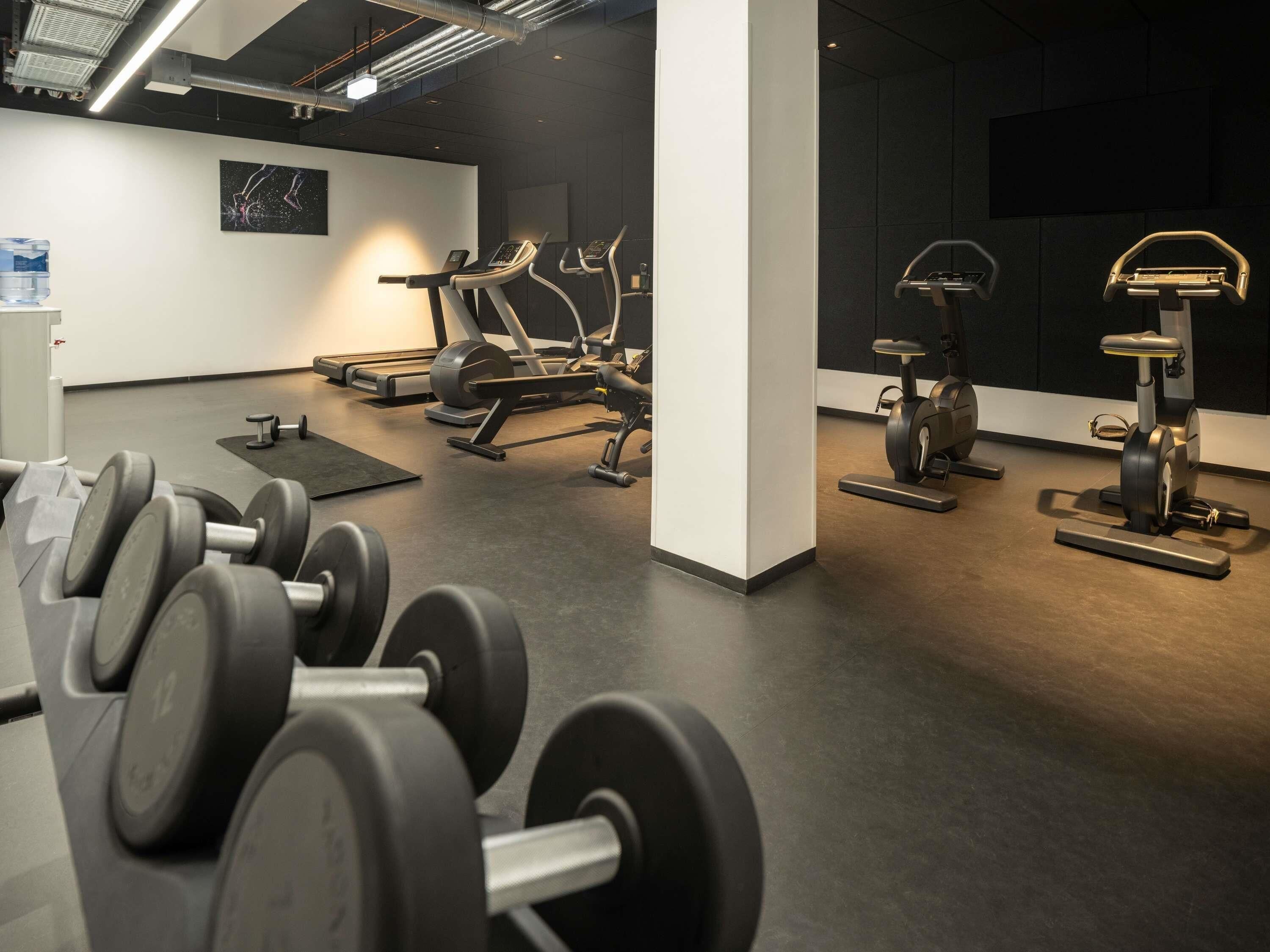 A gym with exercise equipment, a water dispenser, and a wall-mounted TV.
