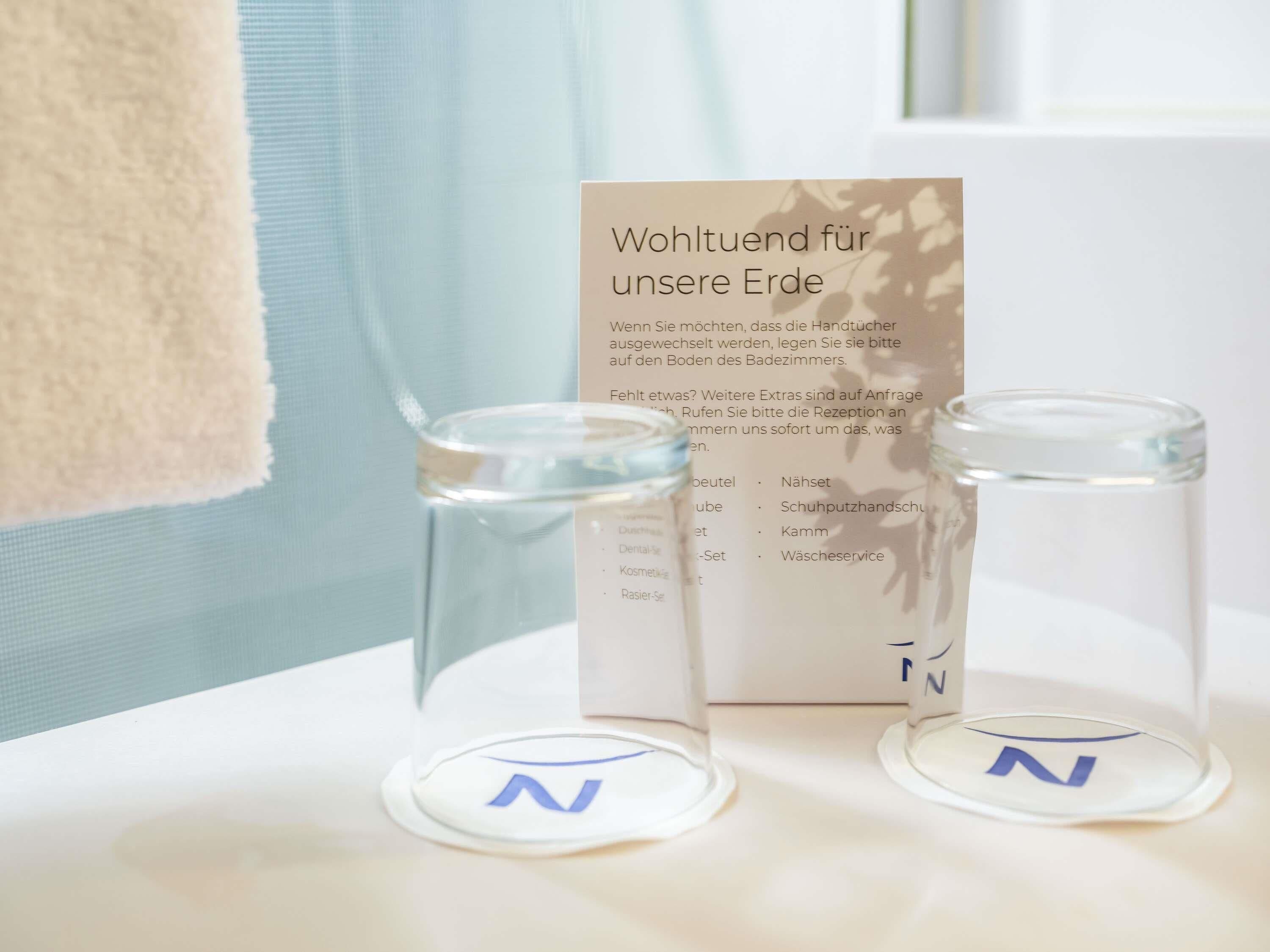 Ein Badezimmer mit einem Handtuch, einem Glasbehälter und einem Schild mit deutschem Text.