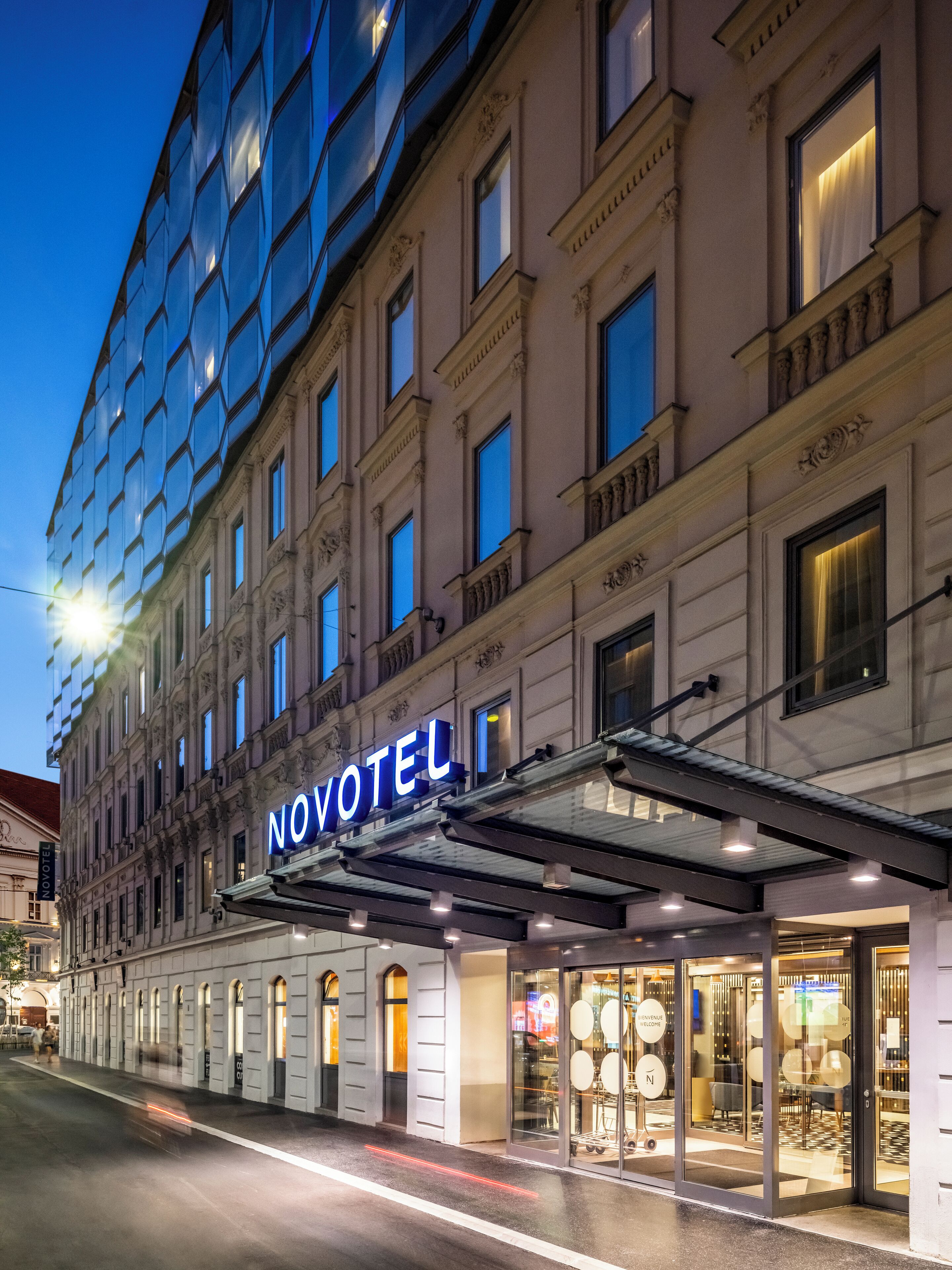 Un hotel con un llamativo letrero 'NOVOTEL', amplias ventanas y una entrada moderna con puertas de vidrio.