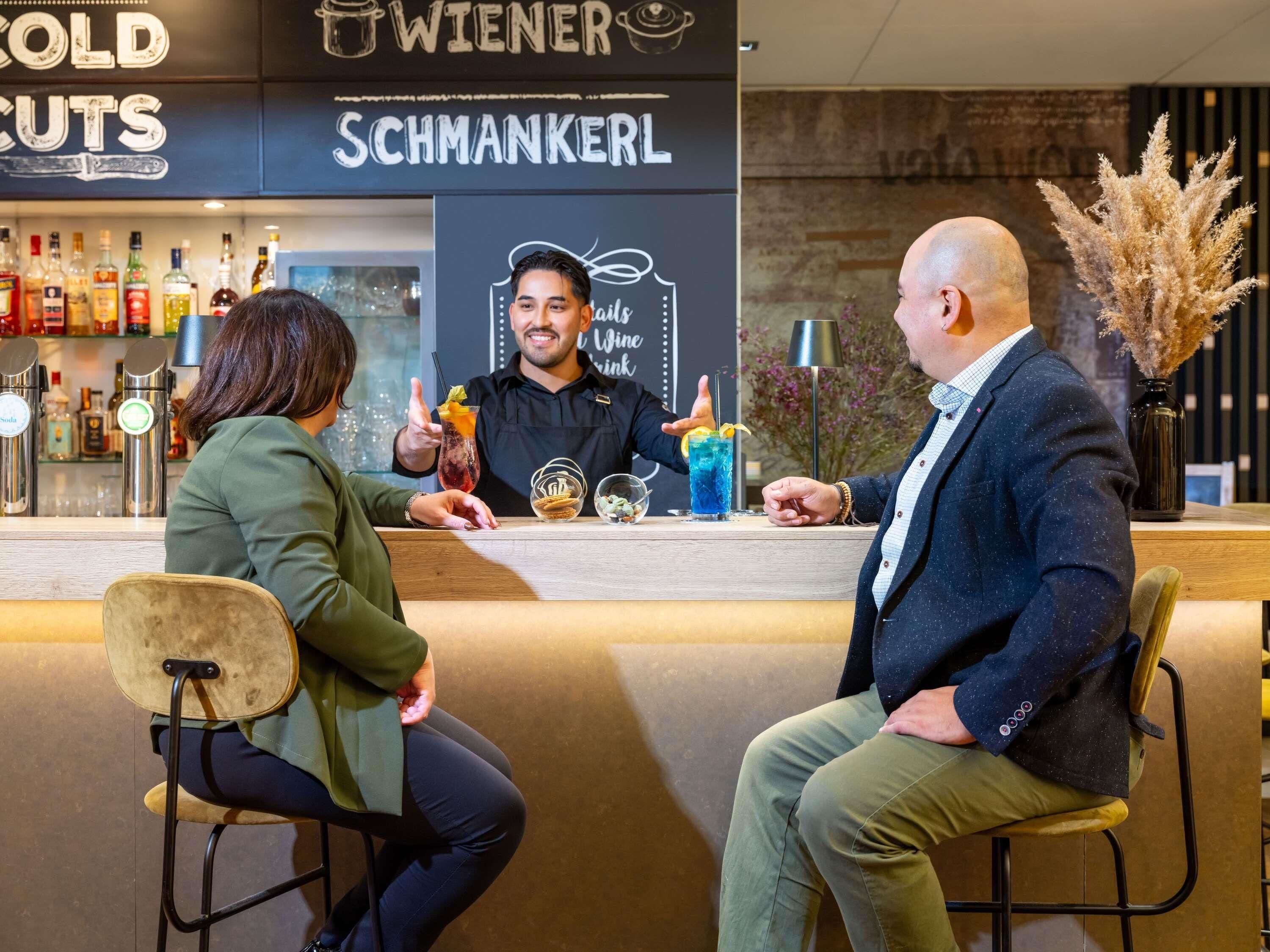 A bar area with a counter, a person serving drinks, and a menu board.