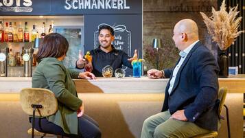A bar area with a counter, a person serving drinks, and a menu board.