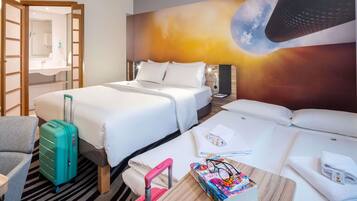 A hotel room with two beds, a desk, a chair, a suitcase, and a wall mural.