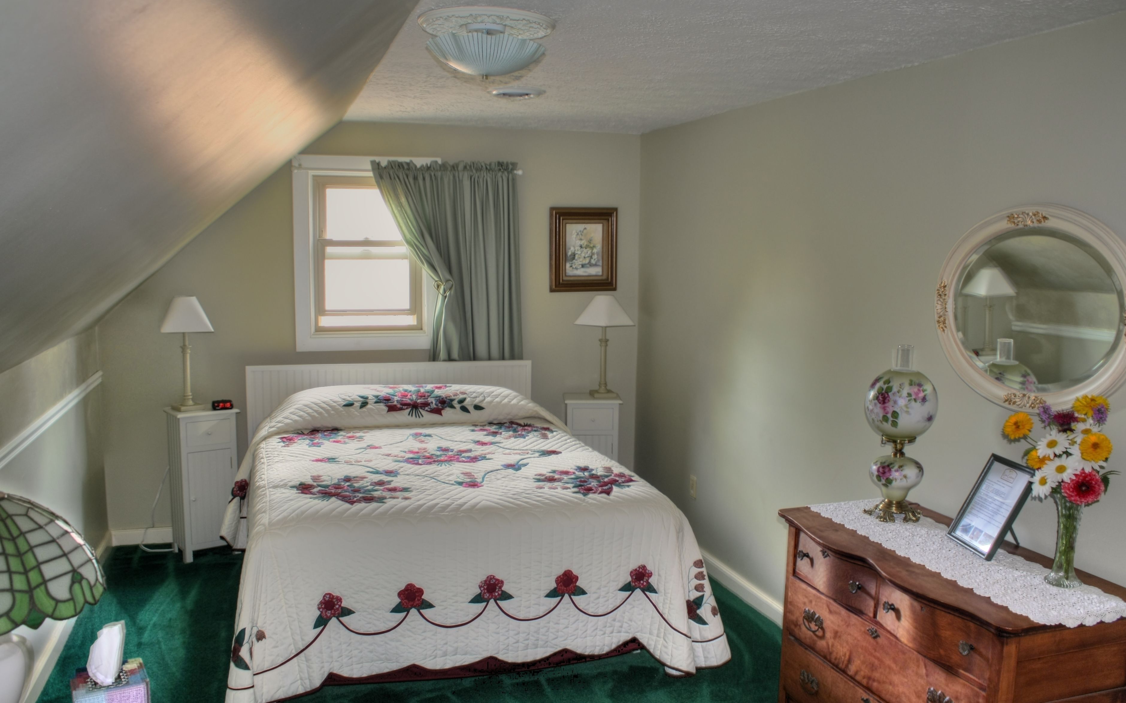 A bedroom with a bed, nightstands, a dresser, a mirror, and a window with curtains.