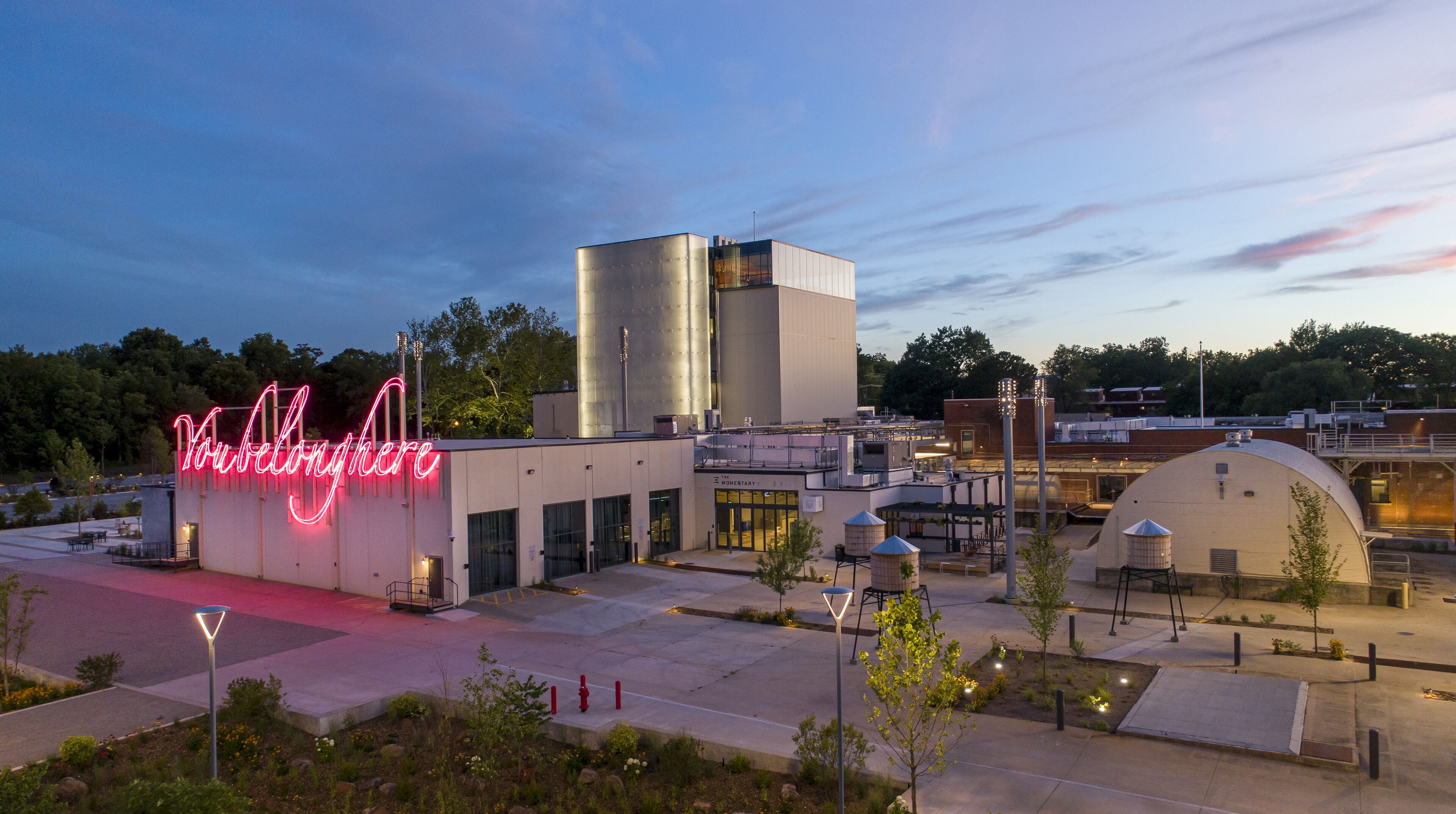 A modern building with a prominent neon sign, a large cylindrical structure, and a dome-shaped building.