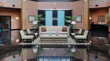 A lobby with a central sofa, two armchairs, a coffee table, and a reception desk.