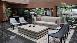 Un vestíbulo con un piano, sofás, sillones y plantas en macetas.