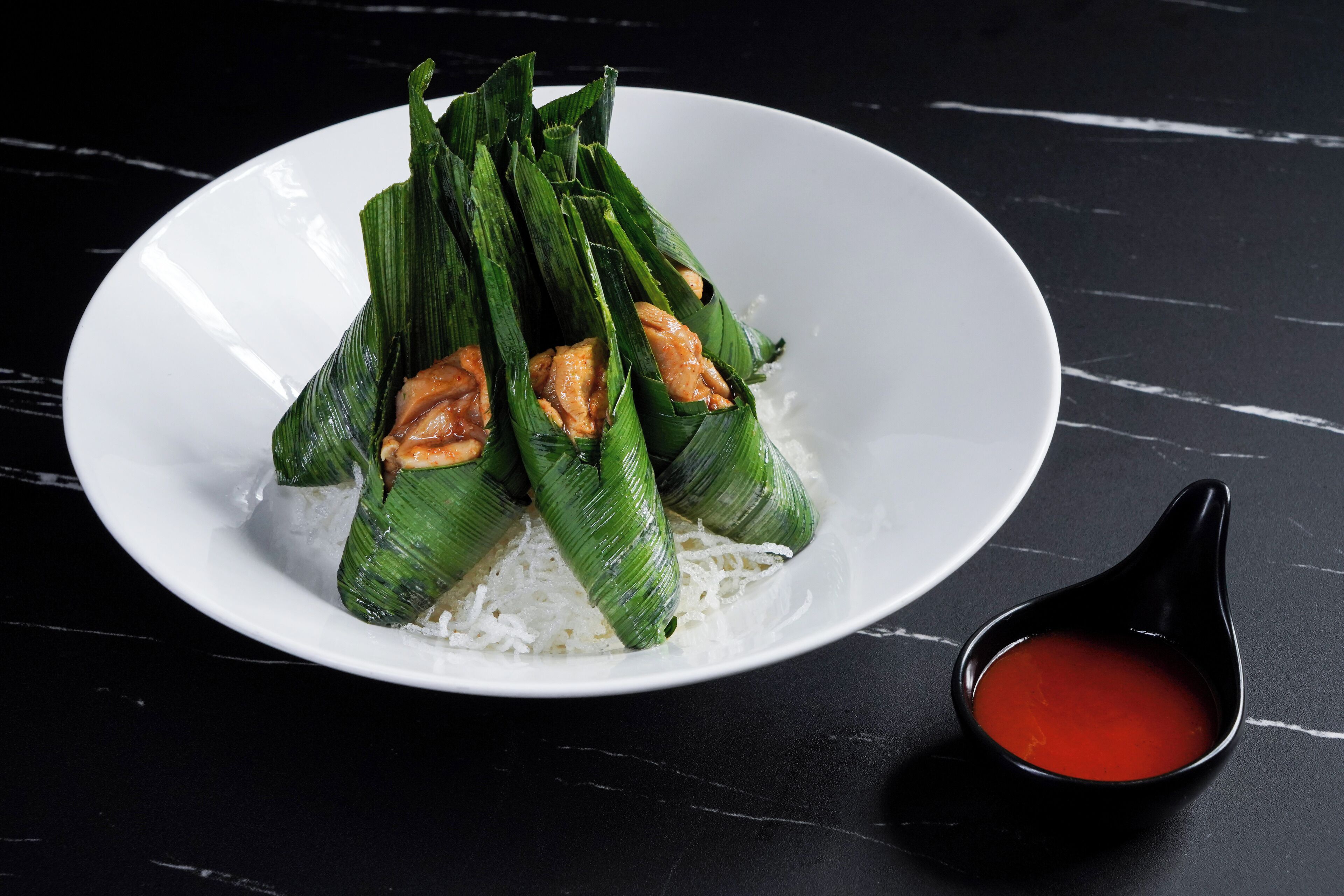 A plate of food with rice and a small bowl of sauce.