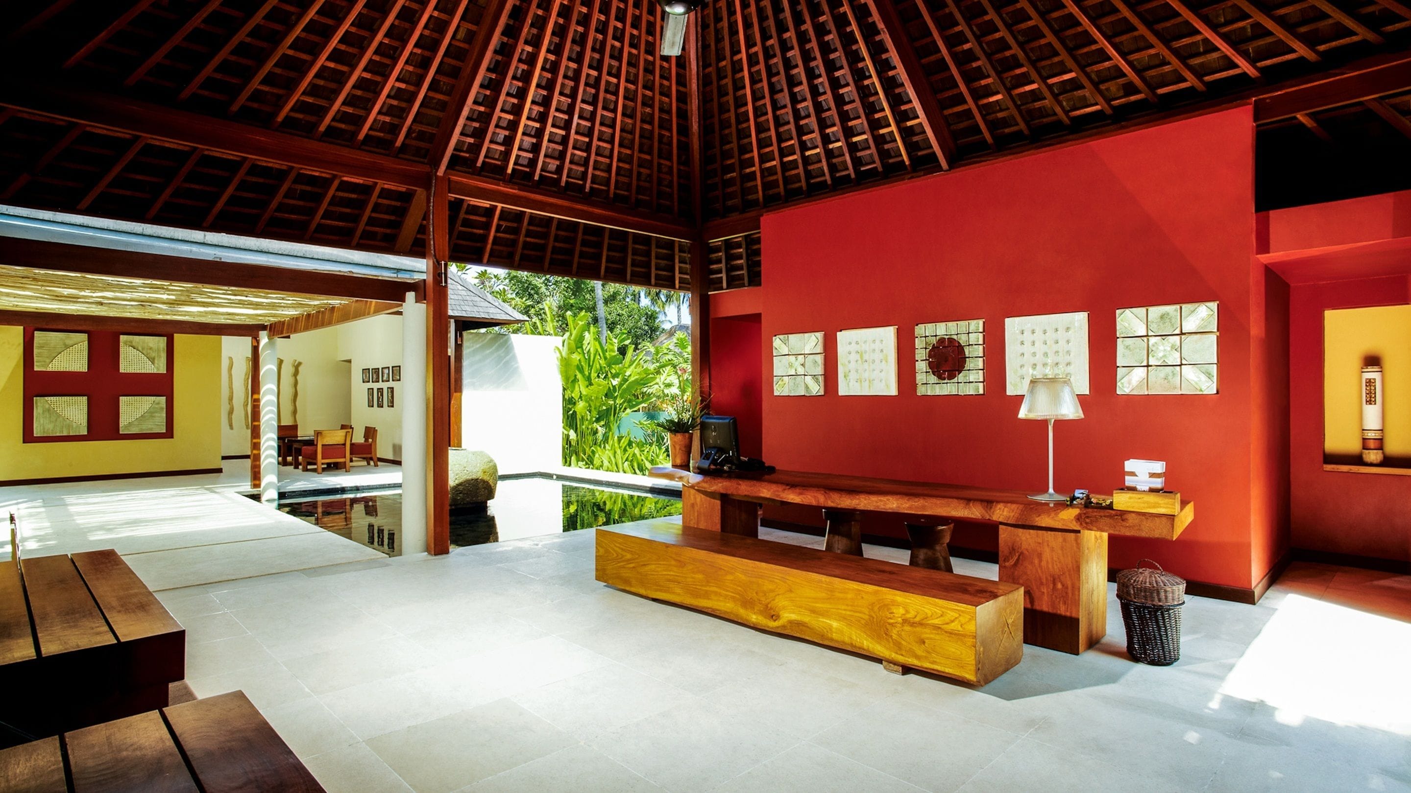 A spacious room with a wooden ceiling, a red accent wall, and a large window overlooking greenery.