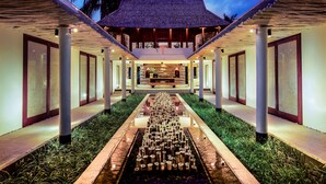 A corridor with a central water feature and a thatched roof structure at the end. - Qunci Villas Resort (Senggigi)