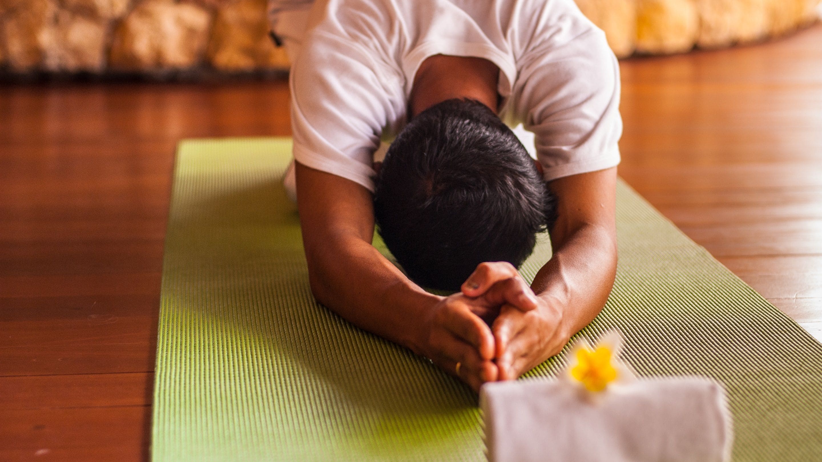 Eine Person führt eine Yoga-Pose auf einer grünen Matte aus.